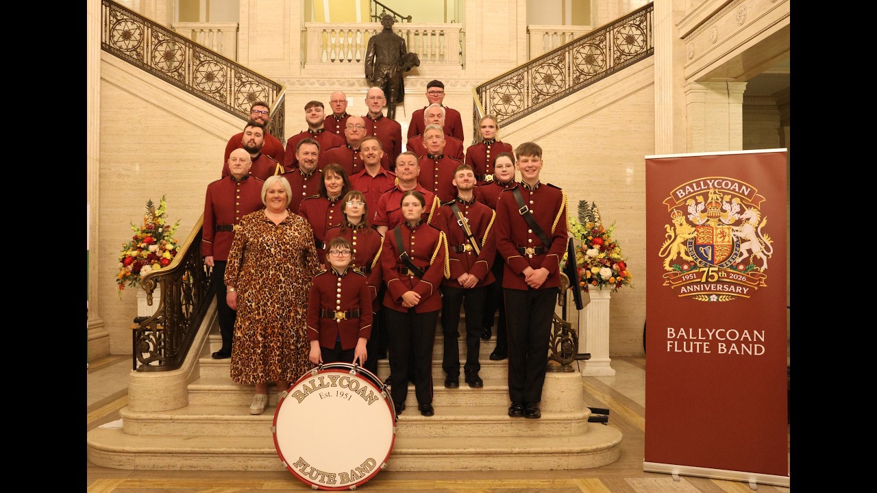 Ballycoan Flute Band group photograph on a staircase with their bass drum and anniversary banner