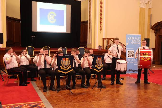 Belfast Boys Model School Flute Band performing indoors with flutes and drums